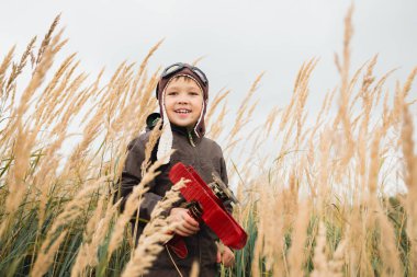 Çocuk gökyüzüne, hayal ve kırmızı bir uçak holding ararken uzun otların arasında duruyor
