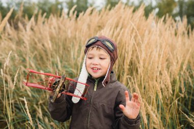 Bir çocuk kırmızı bir uçak ile oynuyor. Çocuk uzun otların bir alana