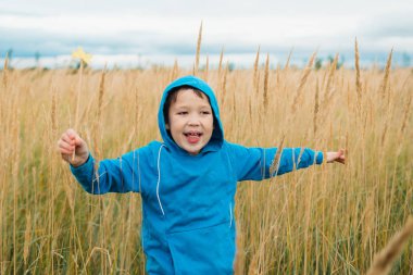 Oyun ve yüksek sarı çim alanda çalışan mutlu çocuk