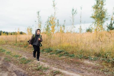 Bir çocuk sonbahar alanında yol boyunca çalışır