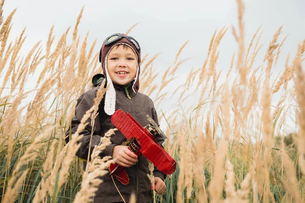 Çocuk gökyüzüne, hayal ve kırmızı bir uçak holding ararken uzun otların arasında duruyor