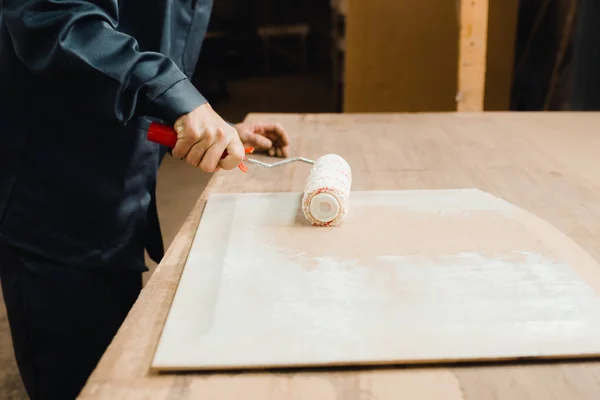 Worker applies glue on a wooden part — Stock Photo, Image