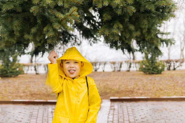 Bir gr bir kolu çekerek bir kukuleta ile sarı bir pelerin içinde mutlu çocuk