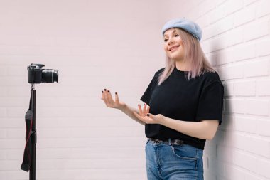 Blog yazarı kameranın önünde. Beyaz tuğla arkaplan.