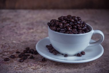 Ahşap ba beyaz seramik bardakta üzerinden dökülen kahve çekirdekleri