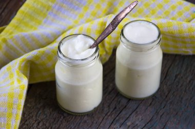 Ahşap masa üzerinde sarı peçete ile beyaz ev yapımı yoğurt