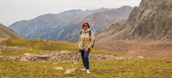 Aged sport woman in sunglasses are standing in the mountains, Ti