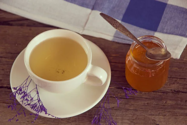 Green tea in a white cup and jar of honey with spoon and blue ki — Stock Photo, Image