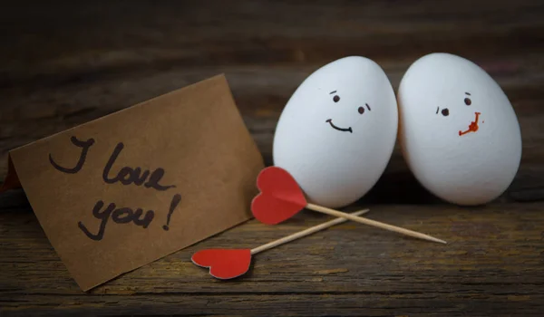 Любовь к двум яйцам, красным сердечкам и открытке с текстом I love you on wooden — стоковое фото