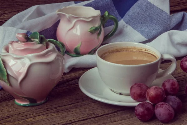 Stilleven met kopje koffie witj melk, rode druiven, roze crocke — Stockfoto