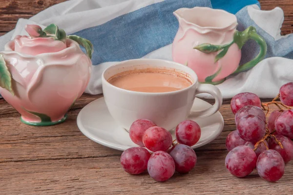 Натюрморт з чашкою кави Witj молока, червоного винограду, рожевого кроку — стокове фото
