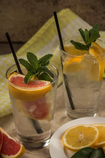 Deux tasses d'eau avec orange rouge, citron, menthe et glace. Fr — Photo