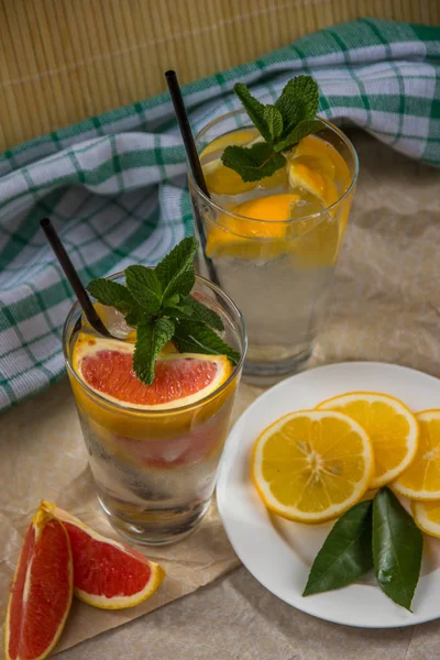 Deux tasses d'eau avec orange rouge, citron, menthe et glace. Fr — Photo