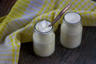 Ahşap masa üzerinde sarı peçete ile beyaz ev yapımı yoğurt