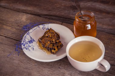 Peteğin ve bal kavanozu ve ahşap zemin üzerine yeşil çay