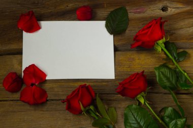 Kırmızı güller ve Beyaz Kağıt ahşap arka plan, üstten görünüm üzerinde boş