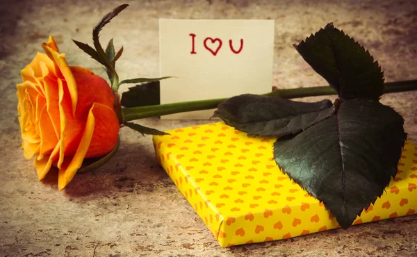 Rose orange, cadeau recouvert de papier de coeur et note que je t'aime — Photo