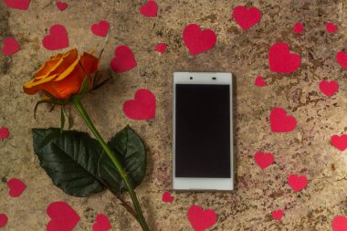 Cep telefonu, gül çiçek ve kalpleri bir ahşap zemin üzerine
