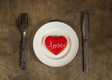 Metin aşk o ve çatal bıçak takımı ile beyaz bir plaka üzerinde kalp kurabiye