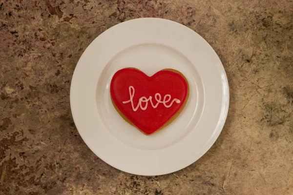 Heart cookie on a white plate with text Love on it — Stock Photo, Image