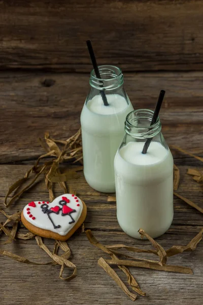 Valentine cookies a mléko v láhvi na dřevěné pozadí — Stock fotografie