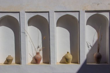 Kemerli bir niş içinde eski kil vazo ile beyaz bir duvar. Eski yaşlı pl