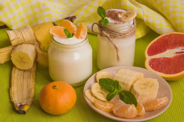 Dessert au lait doux maison bio avec banane, cannelle, mandarine, orange rouge et menthe sur le fond en bois — Photo