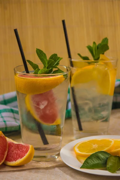 Deux tasses d'eau avec orange rouge, citron, menthe et glace. Fr — Photo