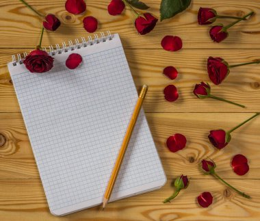 Boş kağıt, kalem ve ahşap arka plan üzerinde kırmızı gül