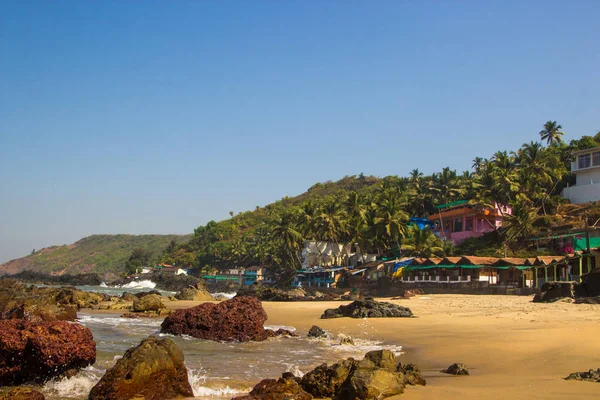 Arambol beach med stenar, palmer och hus, Goa, Indien — Stockfoto