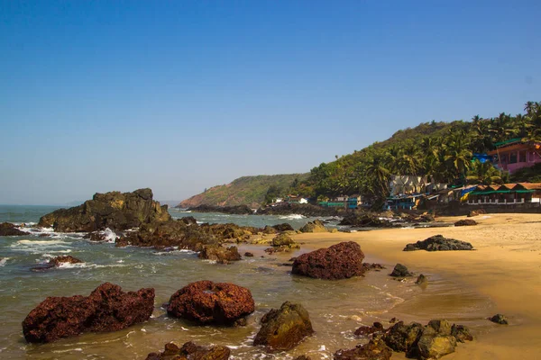 Arambol beach med stenar, palmer och hus, Goa, Indien — Stockfoto