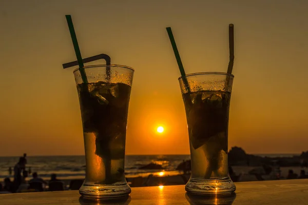 Mojito cocktail on beach, sunset and sea in background