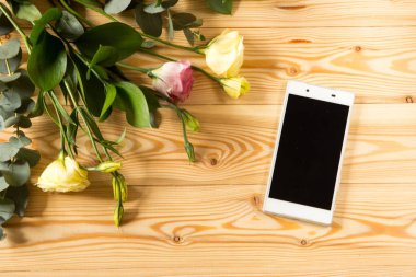 Akıllı telefon ve eustoma ahşap arka plan üzerinde