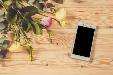 Akıllı telefon ve eustoma ahşap arka plan üzerinde