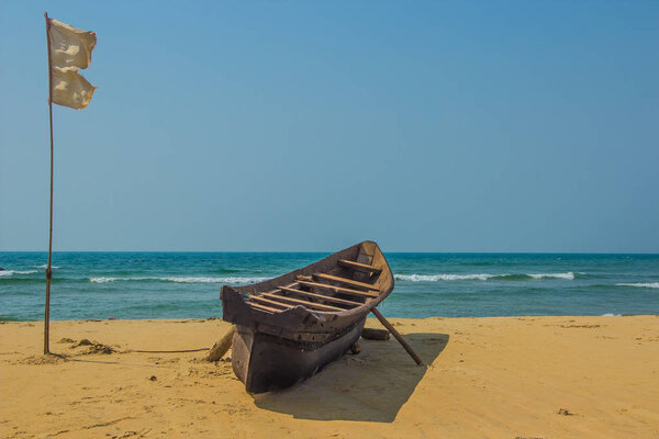 Fishing boat and white flag on sandy beach at Arabian sea. India