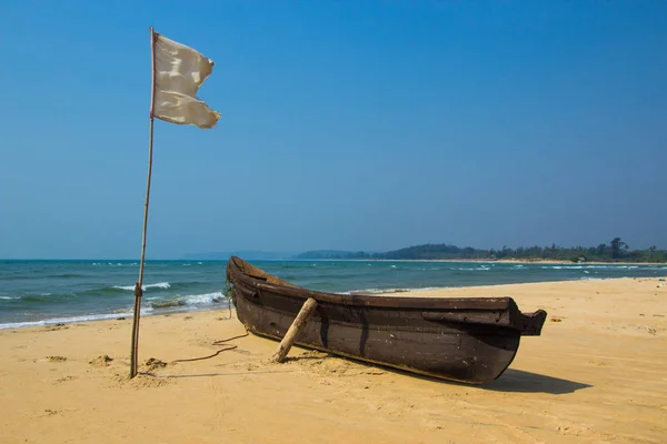 Rybářský člun a bílou vlajku na písečné pláži u Arabského moře. Indie — Stock fotografie