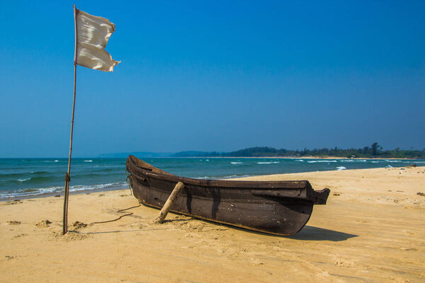 Fishing boat and white flag on sandy beach at Arabian sea. India