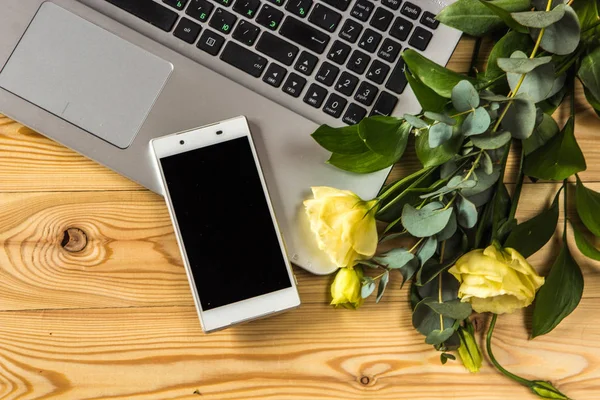Smartphone, dizüstü bilgisayar ve ahşap backgr eustoma çiçekler