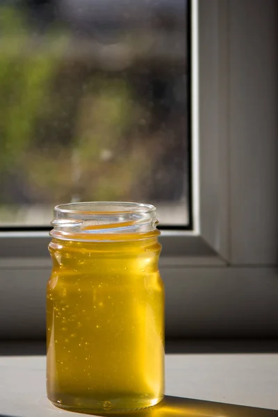 Mel puro orgânico em jarra na soleira da janela — Fotografia de Stock