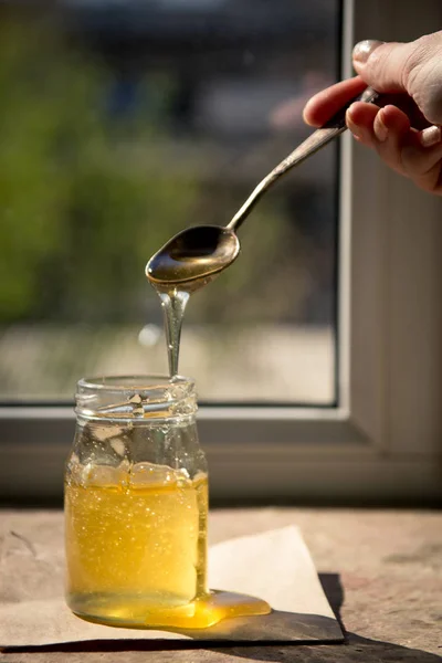 Du miel qui coule d'une cuillère. Miel pur biologique en pot — Photo