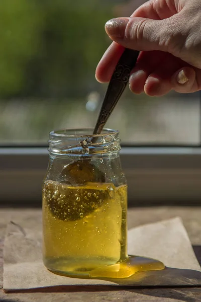O mel a pingar de uma colher. Mel puro orgânico em jarra — Fotografia de Stock