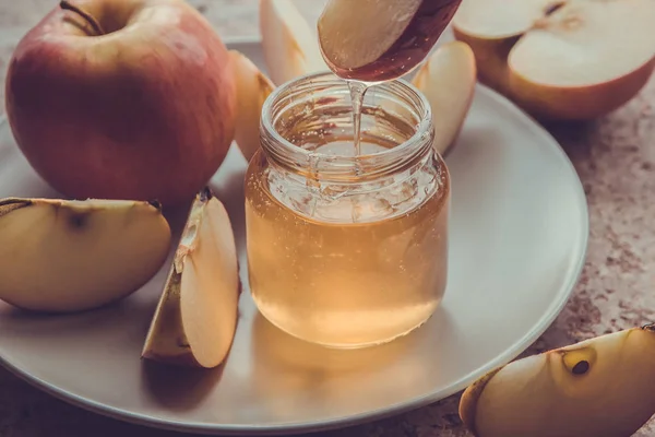 Madu organik dalam botol kaca dan apel merah di piring — Stok Foto