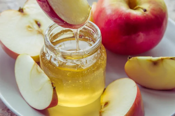 Ekologisk honung i glas burk och rött äpple på plattan — Stockfoto