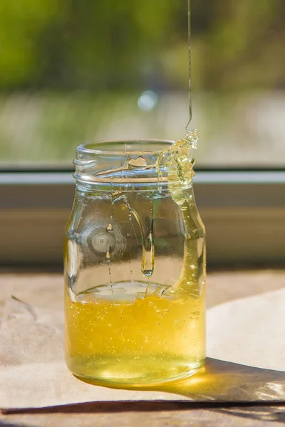 Szerves tiszta méz jar az ablakpárkányon. Patak a méz — Stock Fotó