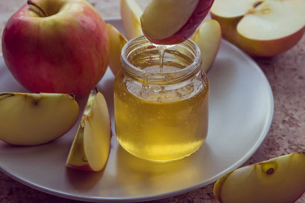 Органический мед в стеклянной банке и красное яблоко на тарелке — стоковое фото