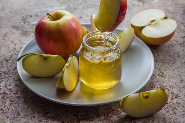 Organic honey in glass jar and red apple on the plate Stock Photo