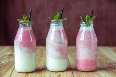 Ahşap masa üzerinde şişelerde çilek ile güler yüzlü