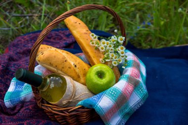 Piknik sepeti beyaz şarap, iki baget ekmek, yeşil elma ve bir 