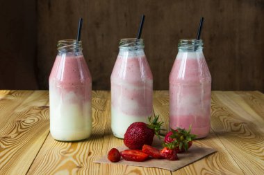 Ahşap masa üzerinde şişelerde çilek ile güler yüzlü