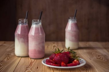 Ahşap masa üzerinde şişelerde çilek ile güler yüzlü